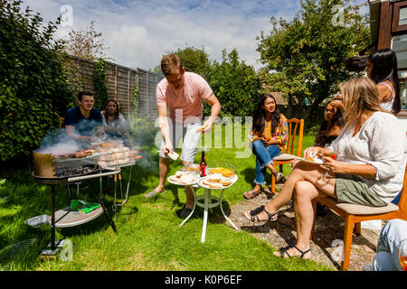Un jeune homme à la cuisson des aliments à une famille traditionnelle, Barbecue, Sussex, UK Banque D'Images