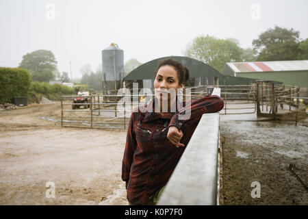 Portrait of Beautiful woman leaning on railing near barn Banque D'Images