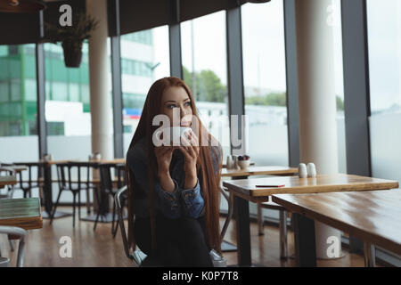 Young woman having coffee while sitting on chair in cafe Banque D'Images