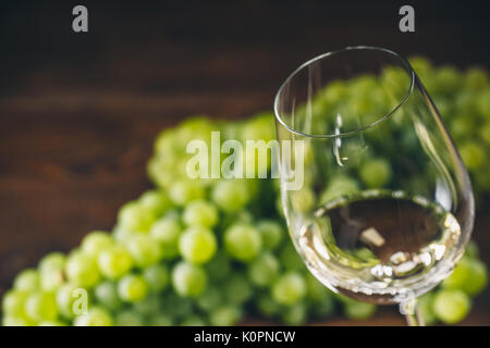 Plein de vin blanc dans des verres à vin avec un tas de raisins verts, sur un fond de bois Banque D'Images