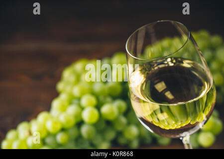 Plein de vin blanc dans des verres à vin avec un tas de raisins verts, sur un fond de bois Banque D'Images