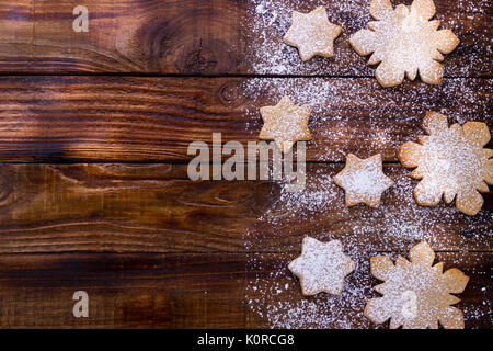 La cuisson de vacances fond, étoiles et flocons de neige gingerbread cookies de sucre glace sur planche de bois, vue du dessus avec copie espace pour le texte Banque D'Images