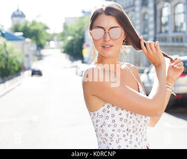 Portrait d'une jeune fille dans une robe blanche et des lunettes permet une coupe sur une journée chaude sur la rue européenne Banque D'Images