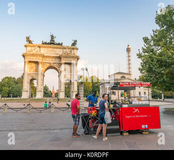 Les habitants et les touristes profiter d'une soirée de détente dans un café en face de l'Arco della Pace (Peace Arch) avec le Castello Sforzesco dans l'arrière-plan Banque D'Images