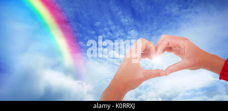 Woman making heart shape avec les mains contre scène tranquille de couvert contre le ciel Banque D'Images