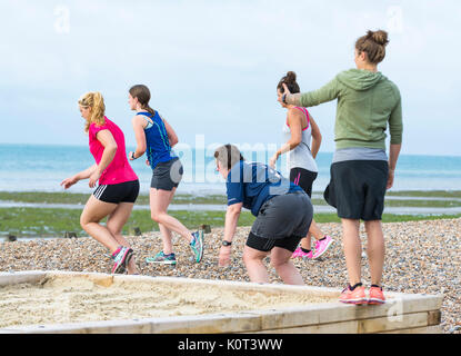 Classe d'exercice sur une plage. Petit groupe de jeunes femmes dans un cours de conditionnement physique l'exercice sur une plage le matin au Royaume-Uni. Banque D'Images