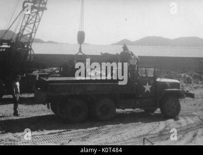 Une photographie de plusieurs officiers de l'armée des États-Unis le déchargement des matériaux de construction d'un camion militaire M35, d'autres matériaux de construction sont situés à proximité de la grue qui est utilisé, Vietnam, 1967. Banque D'Images