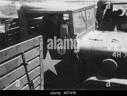 Une photo de deux United States Army M35 camions militaires avec leurs chauffeurs, le pilote le plus proche est posé pour l'image, tandis que l'autre est l'examen de quelque chose dans la cabine du camion, Vietnam, 1967. Banque D'Images