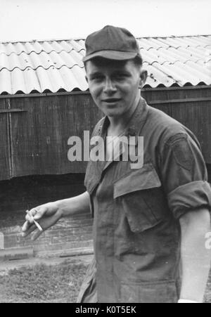 Une franche photographie d'un soldat de l'armée des États-Unis fumer une cigarette tout en interagissant avec le photographe sur la base, Vietnam, 1967. Banque D'Images