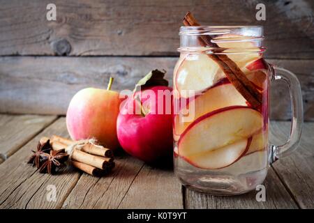 Le thème de l'automne l'eau detox avec Apple, la cannelle et le rouge dans un pot Mason poire sur un fond de bois rustique Banque D'Images