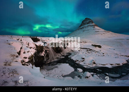 Aurore boréale au-dessus d'une cascade et Kirkjufellsfoss Kirkjufell montagne enneigée, l'Islande Banque D'Images