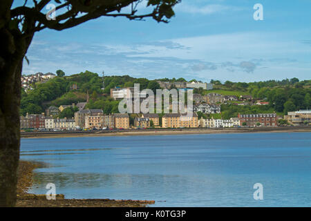 Les bâtiments adjacents et front de colline à ville de Port à côté Bannatyne, une eau bleue de l'océan sous ciel bleu sur l'île de Bute, Ecosse Banque D'Images