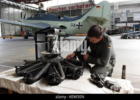 Un mécanicien est le nettoyage du moteur radial d'un avion 3 Farman historique qui a été construit avant la Première Guerre mondiale dans l'hangar de restauration de la direction générale de l'aérodrome de Berlin-Gatow le Musée d'histoire militaire de la Bundeswehr à Berlin, Allemagne, 18 août 2017. Un Fairey Gannet est visible en arrière-plan ; les deux plans seront affichés dans la nouvelle exposition dans le Hangar 3. Photo : Maurizio Gambarini/dpa Banque D'Images