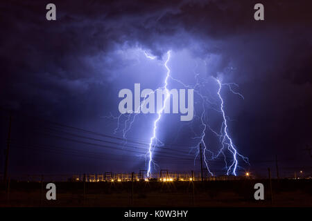 Des éclairs fréquents entre nuages et terre frappent une sous-station électrique alors que des orages de mousson se déplacent dans le désert de Phoenix, en Arizona Banque D'Images