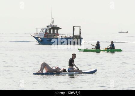 Lyme Regis, dans le Dorset, UK. 25 août 2017. Météo britannique. Deux adolescents bronzer et paddleboarding en même temps sur l'eau dans la chaleur du soleil à la station balnéaire de Lyme Regis dans le Dorset, le vendredi précédant le jour férié d'août. Crédit photo : Graham Hunt/Alamy Live News Banque D'Images