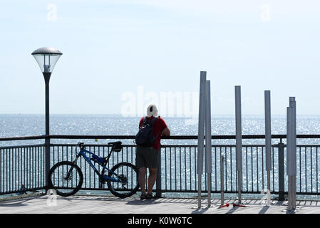 Homme avec vélo debout au bout de Boscombe Pier et vue sur la mer Banque D'Images