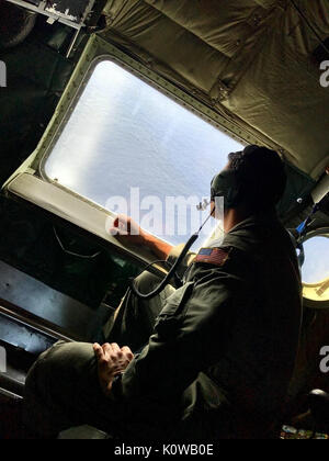 Un aircrewman de la Garde côtière à bord d'un avion Hercules HC 130 de la station de l'air Point barbiers numérise l'eaux de Oahu le 18 août 2017, pour tout signe de cinq aviateurs disparus depuis une armée UH-60 Black Hawk. Les aviateurs ont disparu la nuit du 15 août au cours d'une évolution de la formation. (U.S. Photo de la Garde côtière Station de l'air Point barbiers/libérés) Banque D'Images