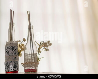 Bouteilles en verre décoratif sur un doux fond rétroéclairé, avec de petites fleurs sur le côté Banque D'Images