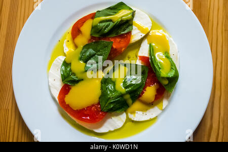 Salade Caprese, avec de la mozzarella, des tomates, basilic, vinaigrette à la moutarde au miel dans les couleurs du drapeau italien : rouge, vert et blanc Banque D'Images