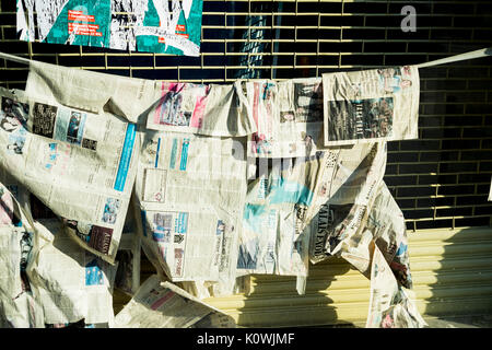 Journaux suspendus sur une ligne comme si de sécher ou de cacher quelque chose à l'intérieur de la fenêtre dans une vitrine dans l'Est de Londres Banque D'Images