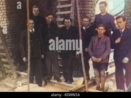 Un groupe d'hommes et de garçons debout sur un chantier en face d'un mur de briques, entouré par des échelles, des cordes et des poutres en acier, en Allemagne, en 1946. Note : l'image a été colorisée numériquement à l'aide d'un processus moderne. Les couleurs peuvent ne pas être exacts à l'autre. Banque D'Images