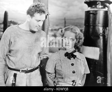 Bette Davis et homme non identifié se tenant ensemble près d'une pompe à essence, Davis avec une expression de colère, dans un film encore, 1949. Crédit photo Smith Collection/Gado/Getty Images. Banque D'Images