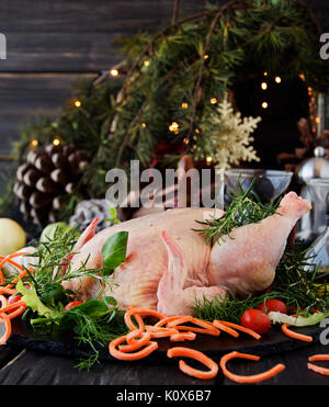 Le poulet cru avec des herbes épices Ingrédients, prêt pour Noël, sur une table en bois, selective focus Banque D'Images