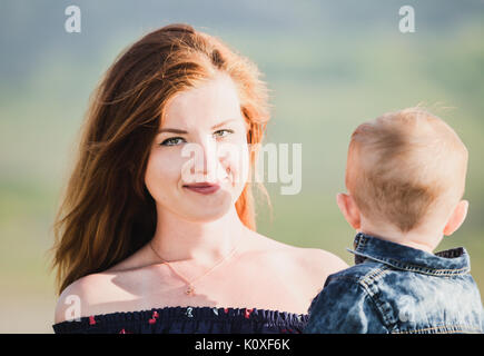 Vue latérale du cheerful beautiful young woman holding baby Banque D'Images