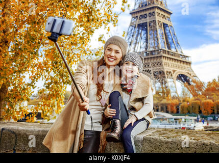 Escapades d'Automne à Paris avec la famille. bonne mère et l'enfant les touristes sur le quai près de la tour Eiffel à Paris, France en prenant l'aide de selfies stic selfies