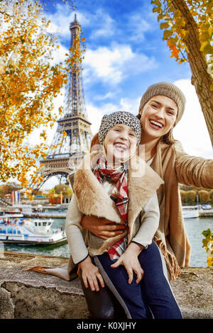 Escapades d'Automne à Paris avec la famille. bonne mère et l'enfant les voyageurs sur le quai près de la tour Eiffel à Paris, France en tenant assis selfies o