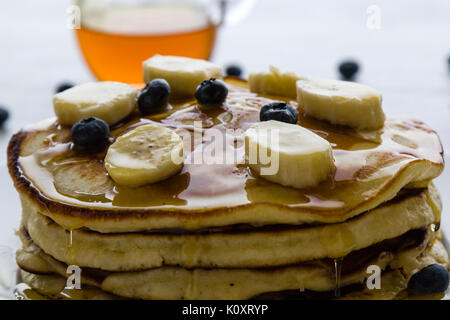 Des crêpes au banane, myrtille et le miel dans la lumière du matin Banque D'Images