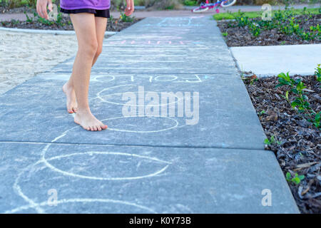 Enfants jouant dans le parc avec la marelle et à la suite de dessins à la craie sur le trottoir Banque D'Images