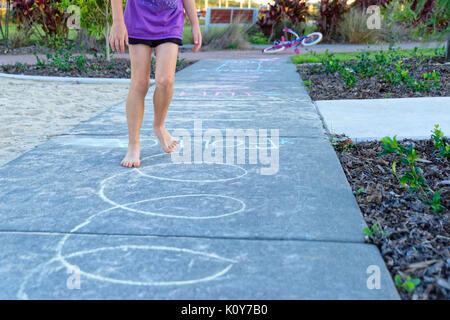 Enfants jouant dans le parc avec la marelle et à la suite de dessins à la craie sur le trottoir Banque D'Images