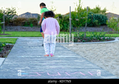 Enfants jouant dans le parc avec la marelle et à la suite de dessins à la craie sur le trottoir Banque D'Images