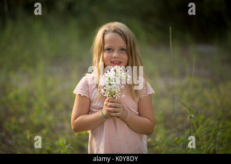 Little girl with bouquet dans la forêt Banque D'Images