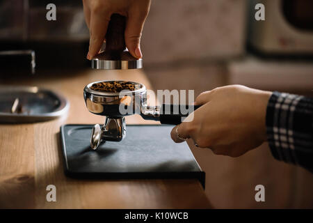 Café barista femelle pilonnage dans un portafilter Banque D'Images