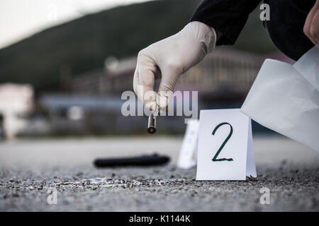 La scène du crime, le meurtre, l'enquête, les manches des coups de servir de preuve, l'enquête est terminée, l'expert prend la capsule des forceps et placés dans Banque D'Images