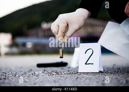 La scène du crime, le meurtre, l'enquête, les manches des coups de servir de preuve, l'enquête est terminée, l'expert prend la capsule des forceps et placés dans Banque D'Images