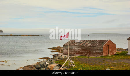 Drapeau canadien flottant à côté d'une cabine de bois L'Anse aux Meadows, péninsule Great Northern, à Terre-Neuve, Canada Banque D'Images