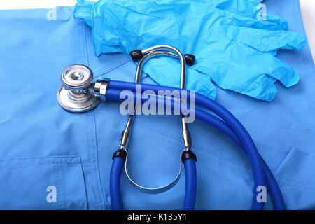 Stéthoscope médical et des gants allongé sur uniforme bleu médecin close up. Le magasin d'instruments médicaux et d'instruments, l'espace de travail du thérapeute, la notion physique de la mesure de la pression artérielle Banque D'Images