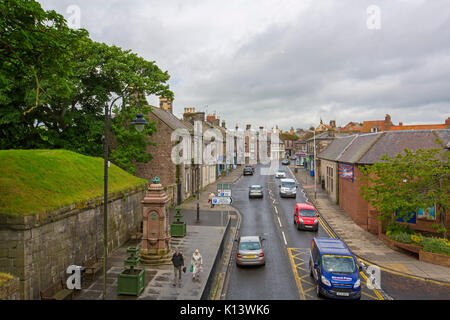 Rue principale de Berwick-upon-Tweed trancheuse à travers la ville de bâtiments historiques, avec les véhicules et les piétons passant vieux mur romain, en Angleterre Banque D'Images