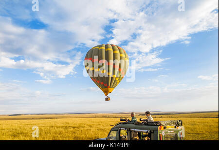 Tôt le matin, les visites touristiques et le visionnement de jeu safari vert coloré en ballon à air chaud sur la plaine de savane et en jeep dans le Masai Mara, Kenya Banque D'Images