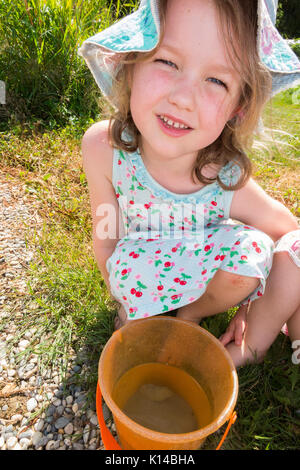 La moitié anglais, moitié français / enfant / kids pour enfants âgés de 5, avec un seau et des petits poissons qu'elle a pris, dans un godet en plastique jouer pendant les vacances en France. Banque D'Images