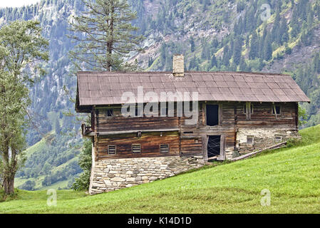 Gîte rural à l'abandon sur le terrain avec des fondations en pierre et murs en bois sur une pente gazonnée verte, Seegut, Grossarl, Autriche Banque D'Images