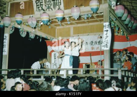 Théâtre Kabuki performance, un homme et une femme dansant ensemble sur scène, les musiciens en arrière-plan, foule visible au premier plan regardant la performance, lanternes suspendues décorant la scène, Japon, 1951. Banque D'Images