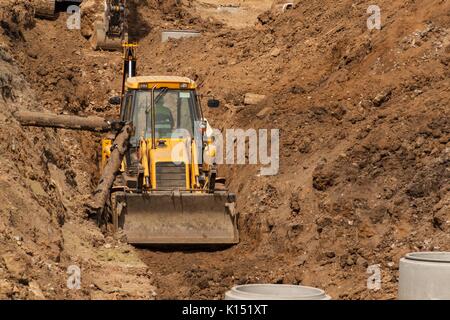 Construction d'un nouveau système d'égout. Le bulldozer creuse une tranchée pour les canalisations d'égout. Les travaux de construction Banque D'Images