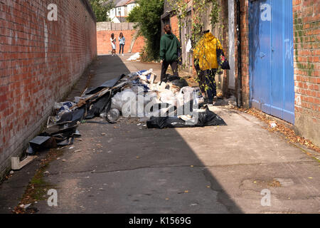 24 août 2017 - Les jeunes femmes en passant devant les détritus et les faisant basculer dans une ruelle contre Cardiff Banque D'Images