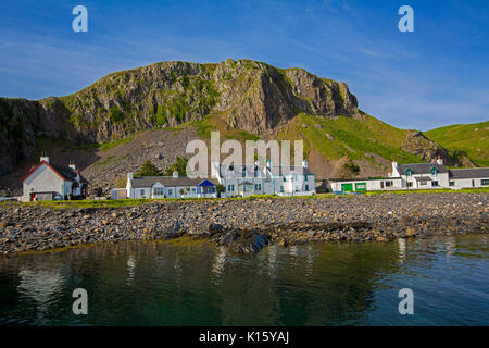 Superbe vue sur le village d'Easdale Ellenabeich /, Seil Island, en Ecosse, avec blanc cottages à la base de la falaise rocheuse reflète dans les eaux calmes de l'océan Banque D'Images