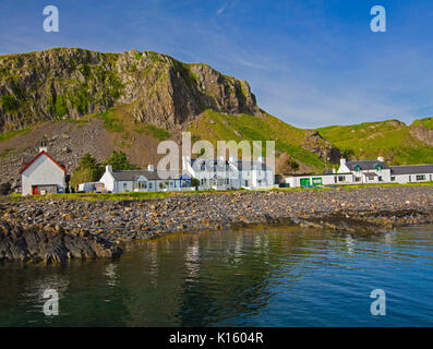 Superbe vue sur le village d'Easdale Ellenabeich /, Seil Island, en Ecosse, avec blanc cottages à la base de la falaise rocheuse reflète dans les eaux calmes de l'océan Banque D'Images