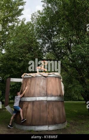 Le gars embrasse un énorme beer mug en bois dans le parc de la ville. Banque D'Images